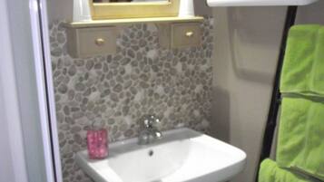 Un baño con lavamanos blanco, un espejo, toallero y un inodoro.