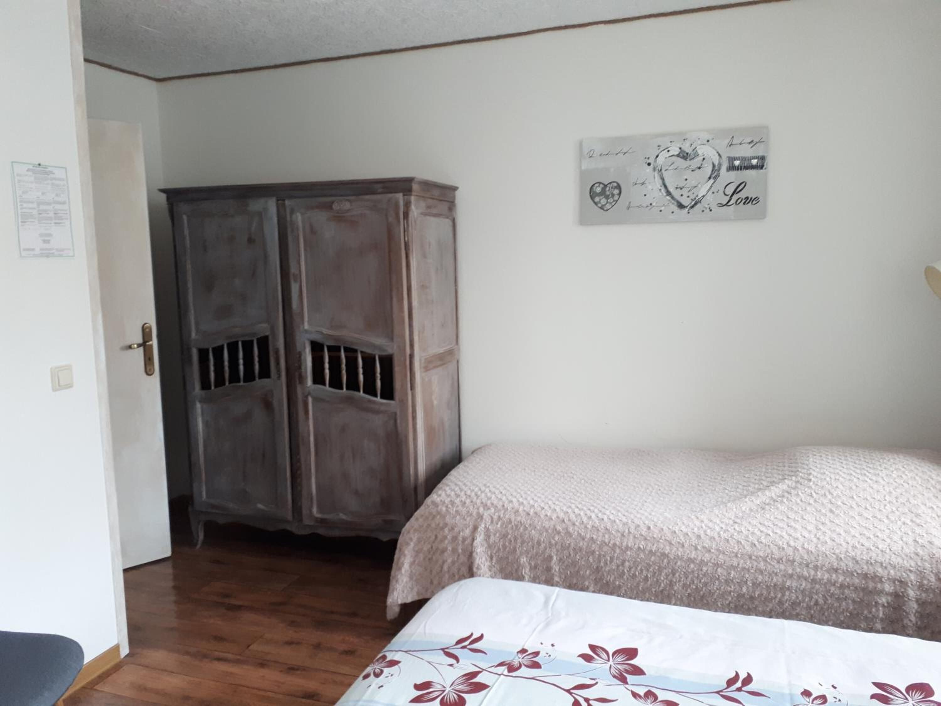 Un dormitorio con cama, armario y un adorno en la pared.