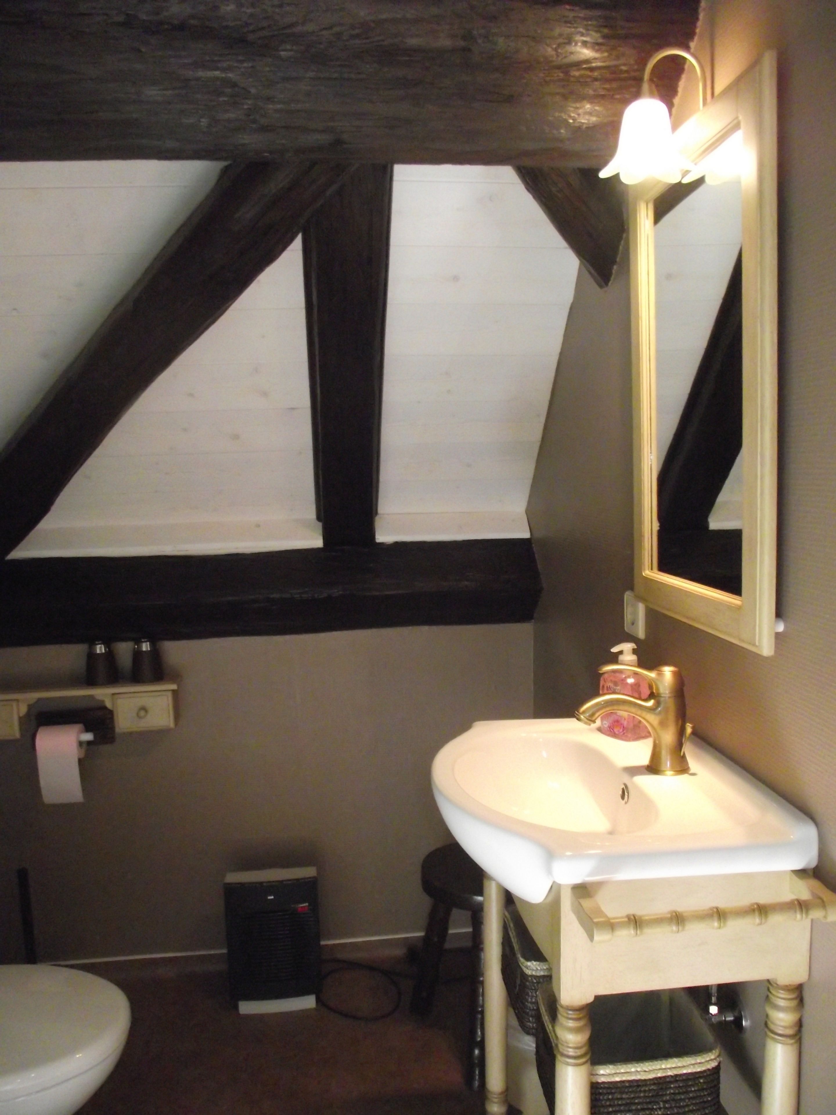 A bathroom with a white sink, a mirror, and a toilet. There is a window above the sink, and a heater is visible on the floor.