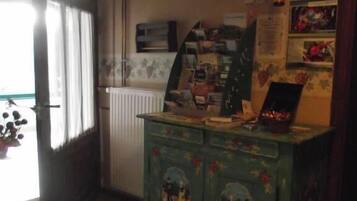 A room with a green cabinet with floral designs, a microwave, and a refrigerator.