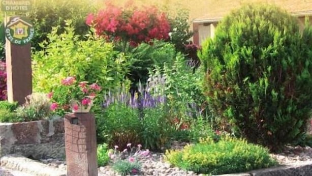 Un jardín con diversas plantas y un pilar de ladrillo.