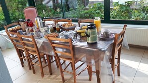 Una mesa de desayuno dispuesta con diversos alimentos y bebidas, rodeada de sillas de madera.