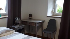Un dormitorio con cama, escritorio, silla y ventana.