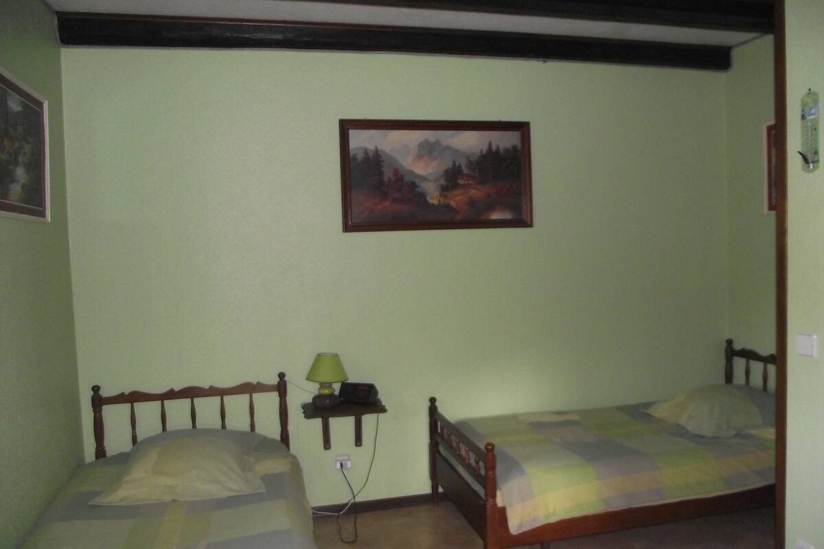 Ein Zimmer mit zwei hölzernen Betten, einem Nachttisch mit Lampe und einem Bild an der Wand.