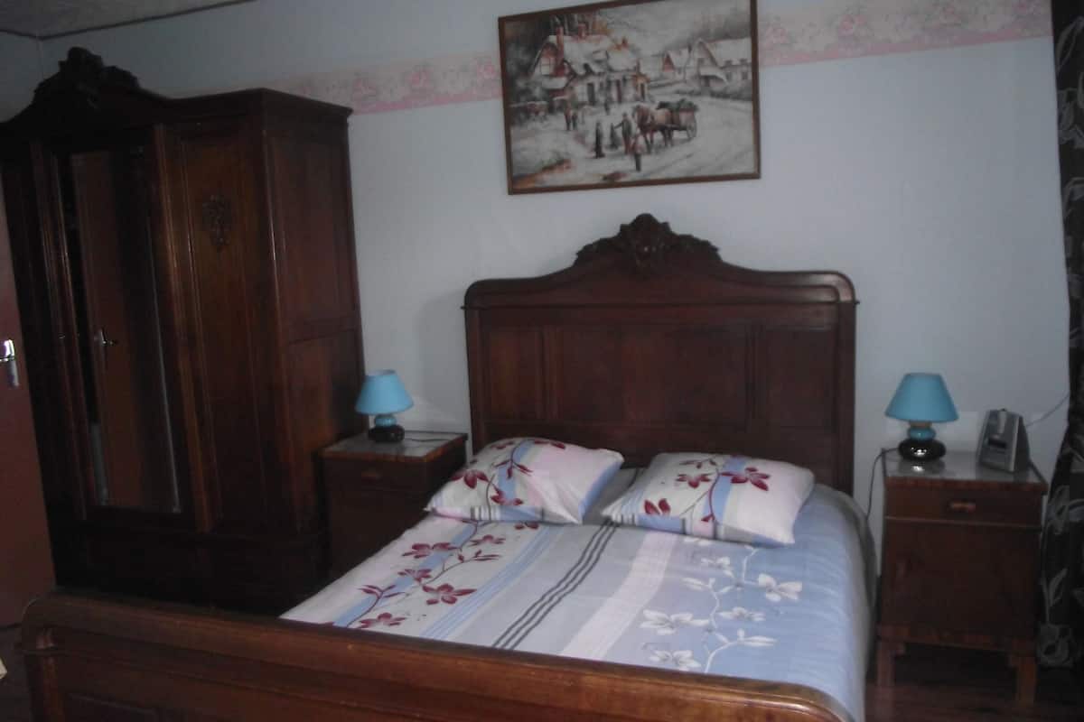 Ein Schlafzimmer mit einem hölzernen Bett, zwei Nachttischen, einem Kleiderschrank und einem Bild an der Wand.