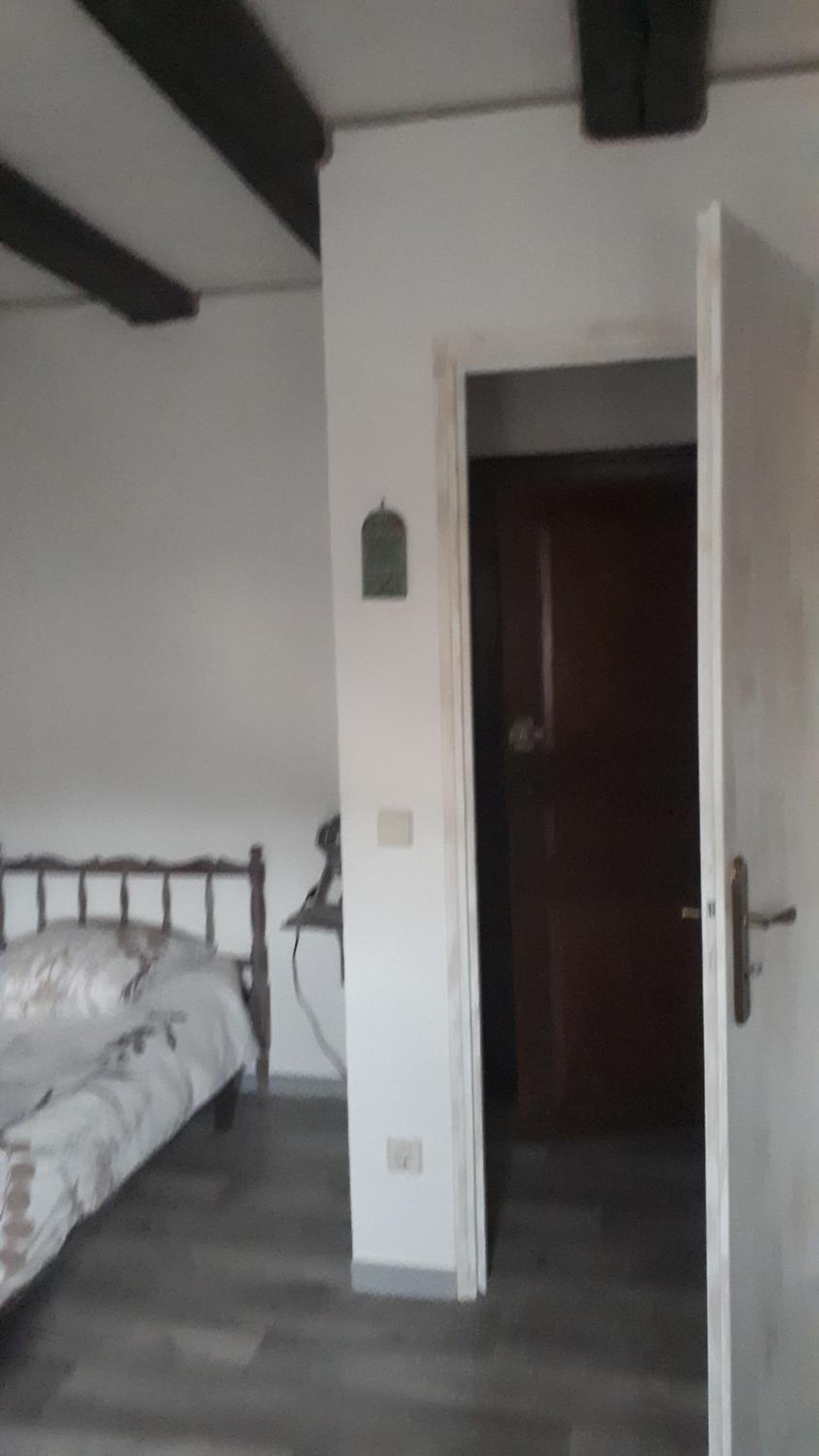 Une chambre à coucher avec un lit, une porte et une petite étagère fixée au mur.