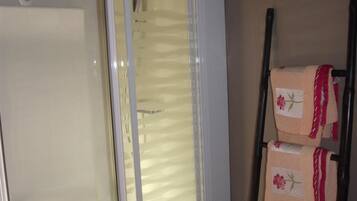 Een badkamer met een douchecabine van glas, een witte badkuip en een handdoekrek met opgevouwen handdoeken.