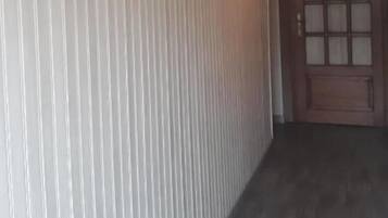 A hallway with vertical striped wallpaper, a wooden door with glass panels, and two framed pictures on the wall.