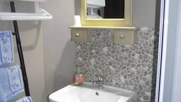A bathroom with a white sink, a mirror with a gold frame, a towel rack with blue towels, and a soap dispenser.