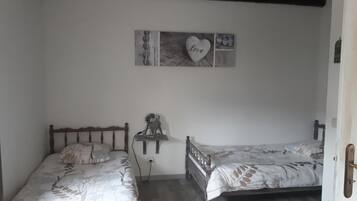A bedroom with two wooden beds, a wall-mounted shelf, and a 'Love' sign.