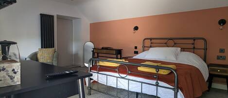 A bedroom with a bed, a desk, and a chair.