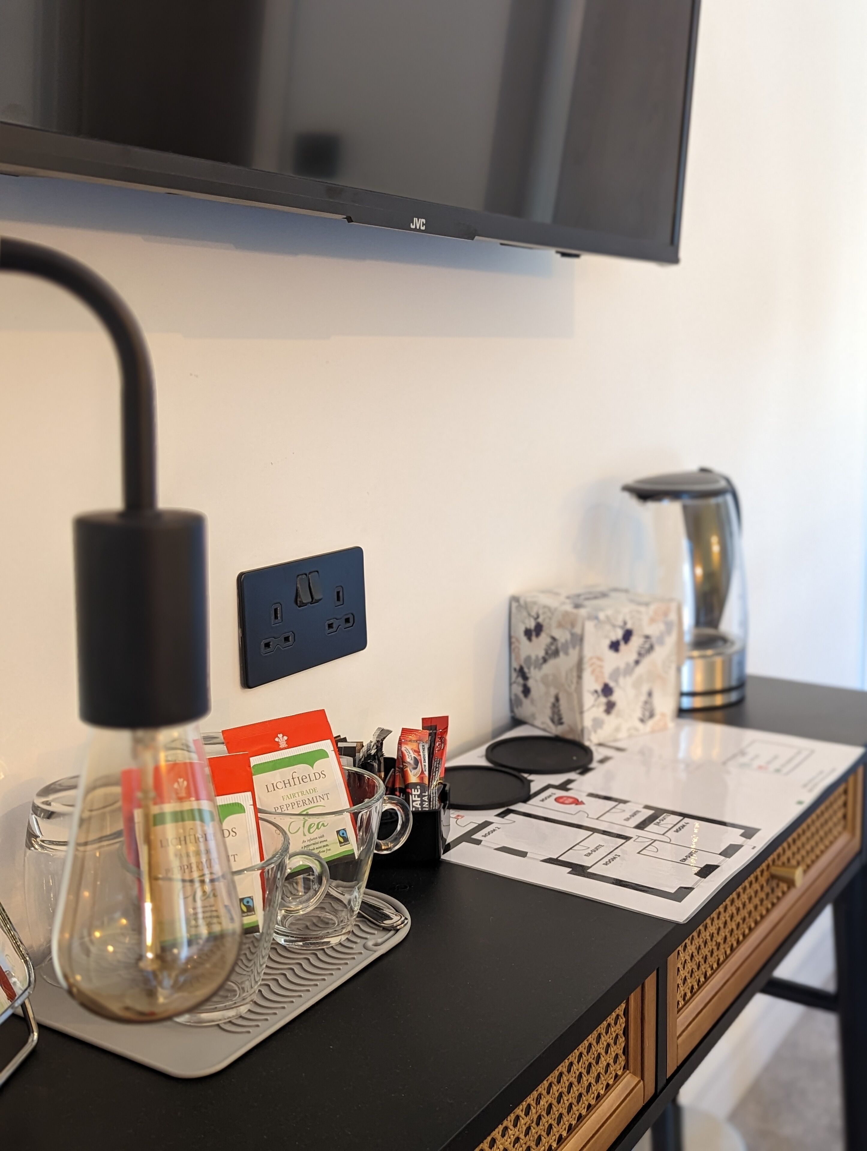 A bar area with a TV mounted above, a coffee machine, and a glass display with coffee pods and a menu.