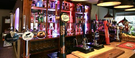 Eine Bar mit mehreren Zapfhähnen für Bier, darunter Marken wie Guinness und Carling, und einer Auswahl an Spirituosenflaschen in Regalen.