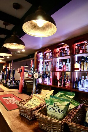 Uma área de bar com várias torneiras de cerveja, prateleiras cheias de garrafas de bebidas e cestos de vinagre de maçã Pipers.