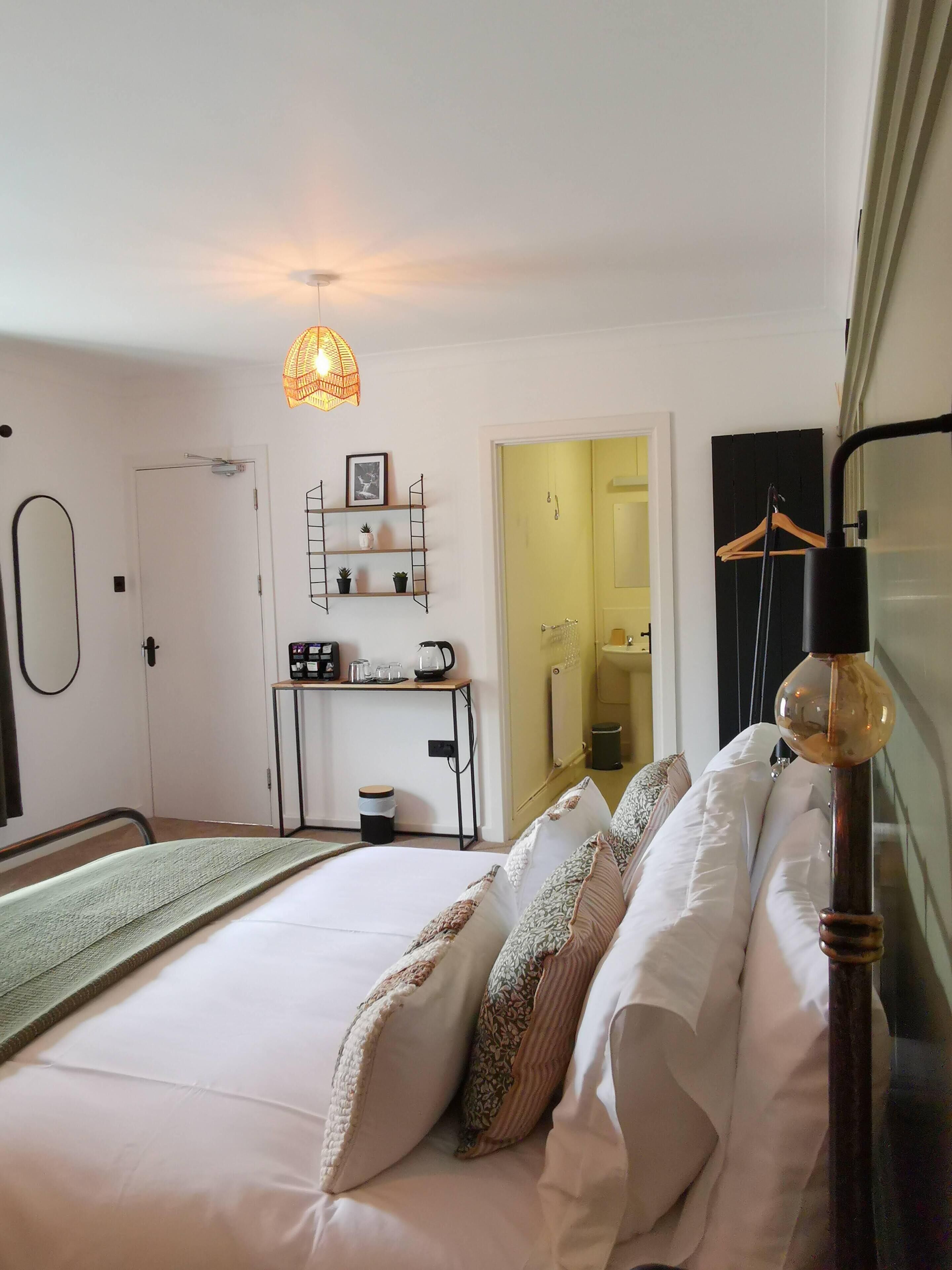 A neatly arranged bedroom with a bed, bedside table, and a hanging light fixture.