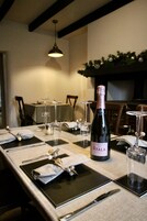 Una mesa de comedor dispuesta con individuales negros, cubiertos y una botella de champán.