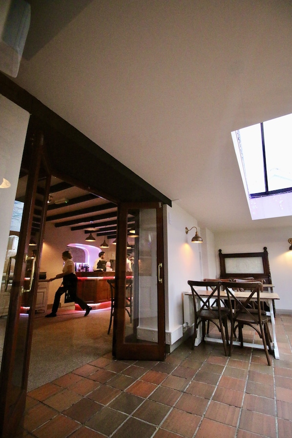 An interior with a high ceiling, a skylight, a bar area, and a dining area with chairs. - The Wolfe Inn Wolfscastle (Haverfordwest)
