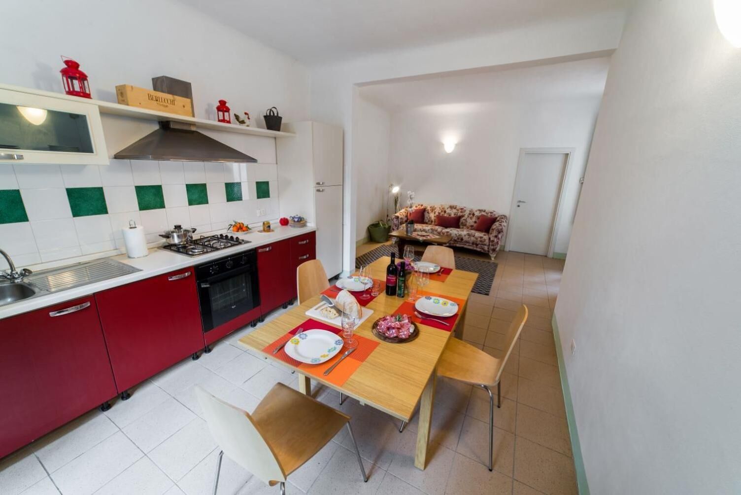 A compact kitchen with a dining area, featuring a stove, sink, and a dining table set for four.