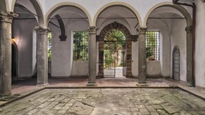 A courtyard with arches, columns, and a gate. - Corte Meraviglia - Relais (Lucca)