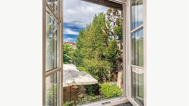 A view through a window with a stone wall and greenery outside. - Corte Meraviglia - Relais (Lucca)