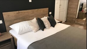 A neatly made bed with a wooden headboard, a bedside table, and a white rug. - Pula Antic Rooms in Center- Adults only (Pula)