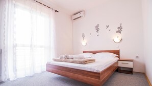 Un dormitorio con cama de madera, una mesita de noche, aire acondicionado de pared y luces decorativas en la pared.