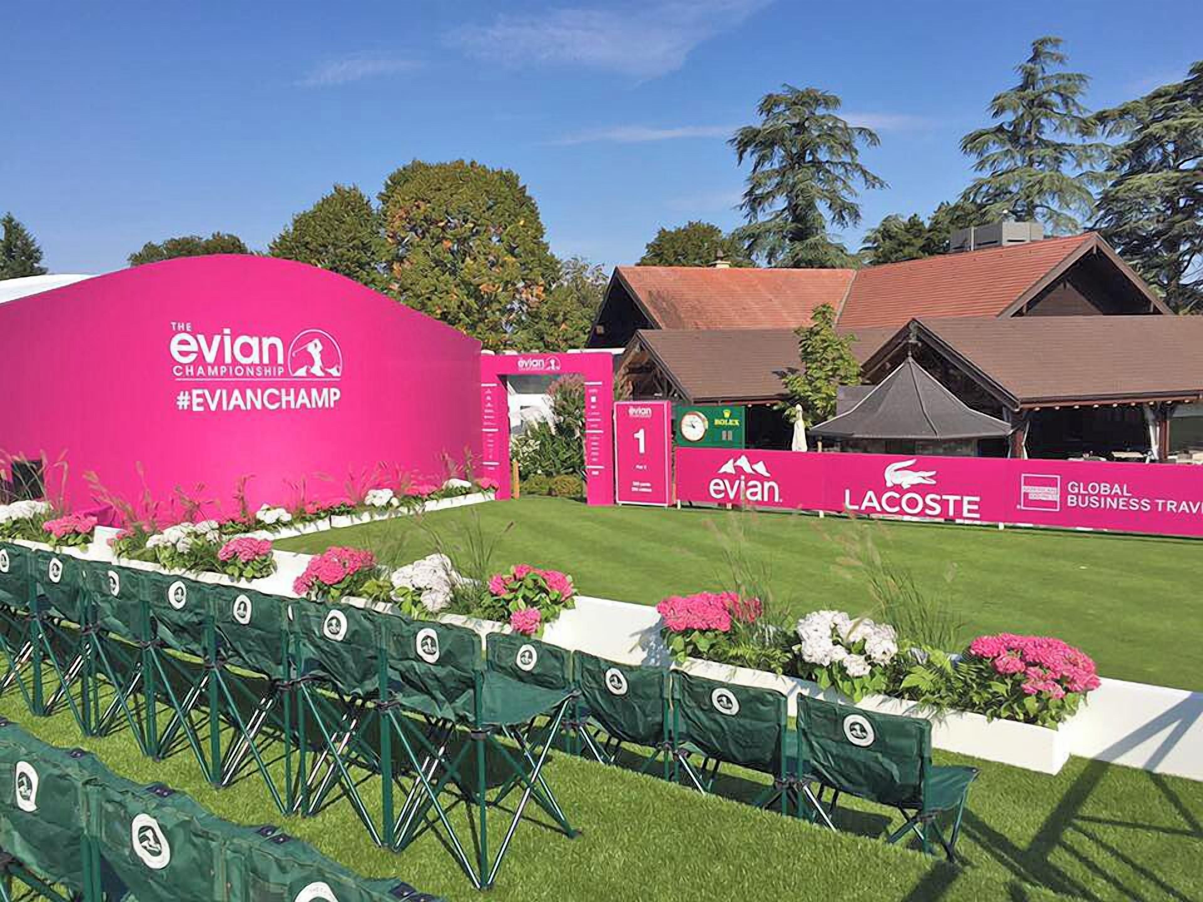 Un parcours de golf avec un pavillon rose portant l’inscription « The Evian Championship » et un tableau d’affichage.