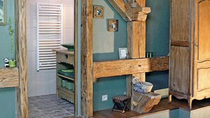Een rustieke zolderkamer met zichtbare houten balken, een houten bank en een kleine tafel.