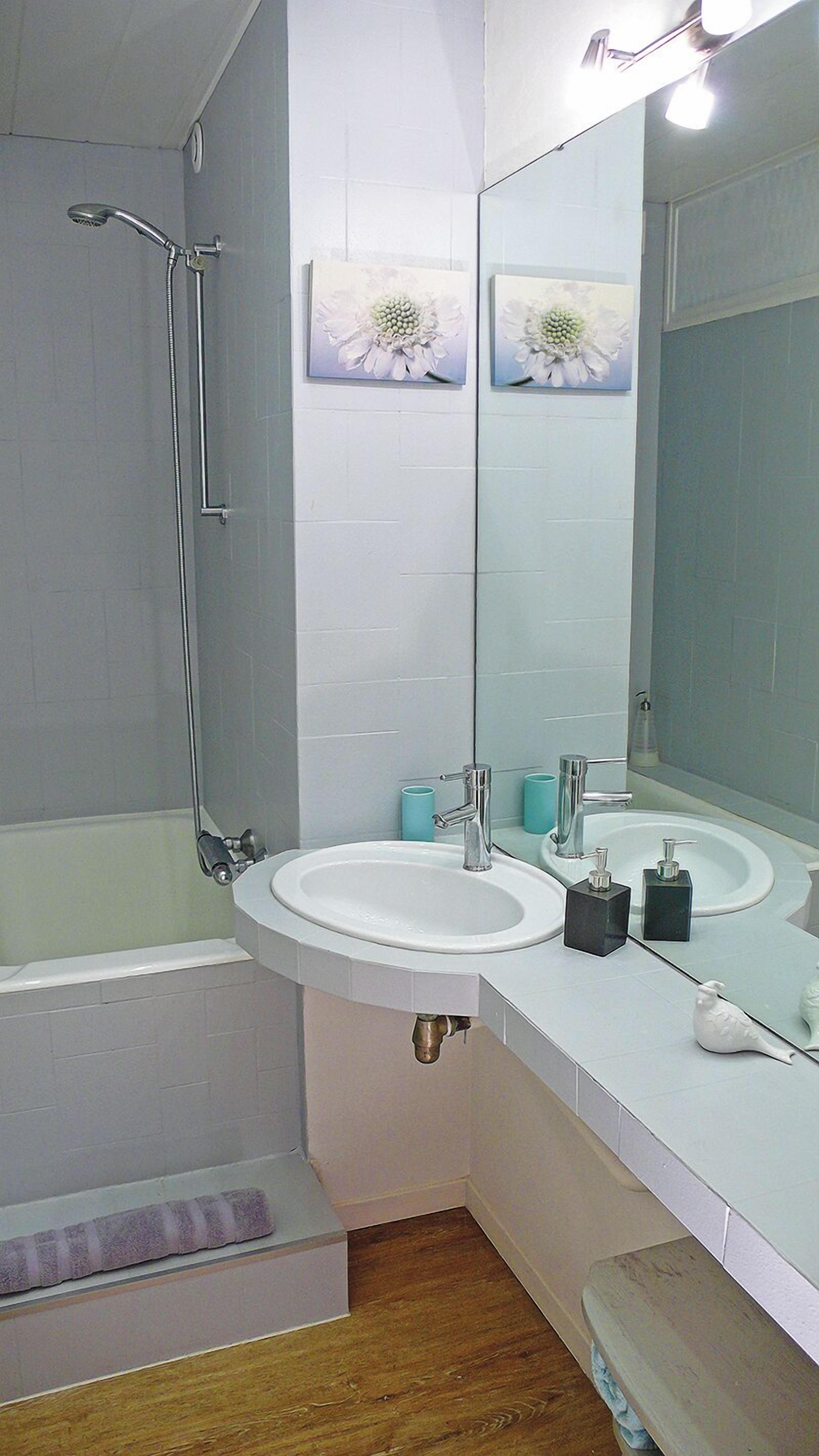 Une salle de bain avec une douche, deux lavabos, un grand miroir et des toilettes.