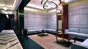 A modern lobby with a sofa, coffee table, and a large mirror.