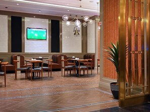 A hotel lobby with seating arrangements, a television screen, and a decorative wall. - Batoul Ajyad (Makkah)