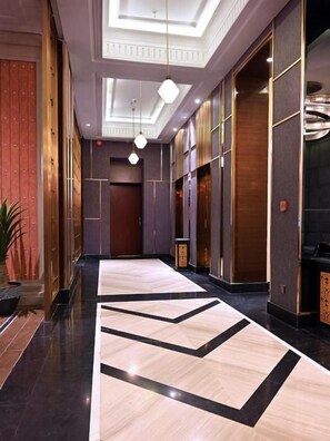 Et hotel med en geometrisk gulvbelægning, en reception og en moderne elevator.