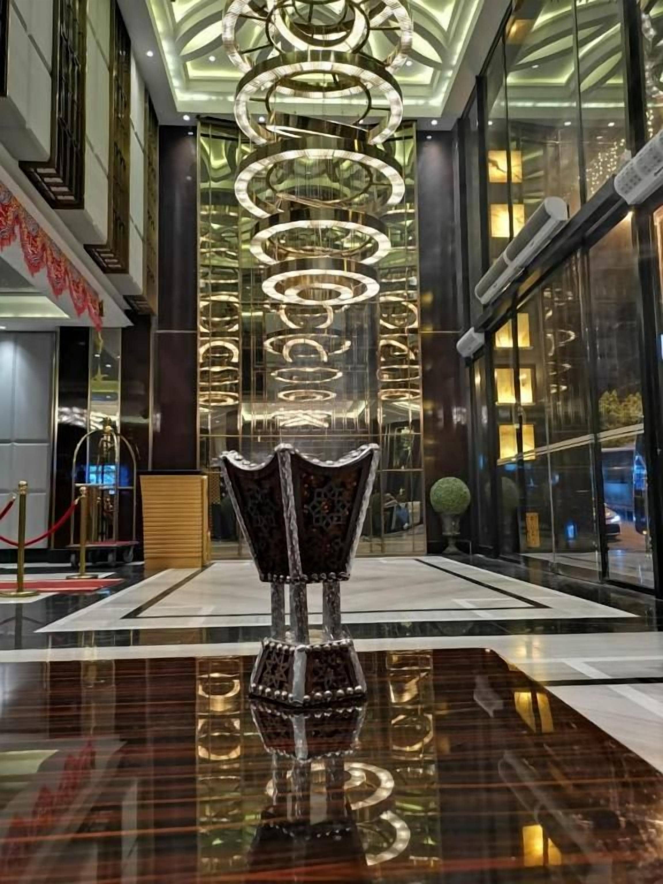 A lobby with a reflective floor, a decorative vase, and a modern chandelier.