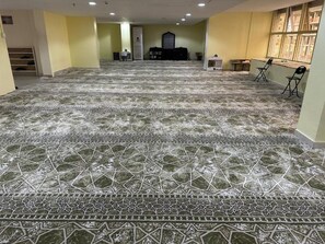 A spacious room with a patterned floor, a reception desk, and chairs near a window. - Batoul Ajyad (Makkah)