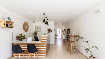 A reception area with a wooden desk, black chairs, and a potted plant.