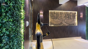 Una estatua de un pájaro con una figura dorada, una pared con jeroglíficos egipcios y un panel de madera con líneas verticales.
