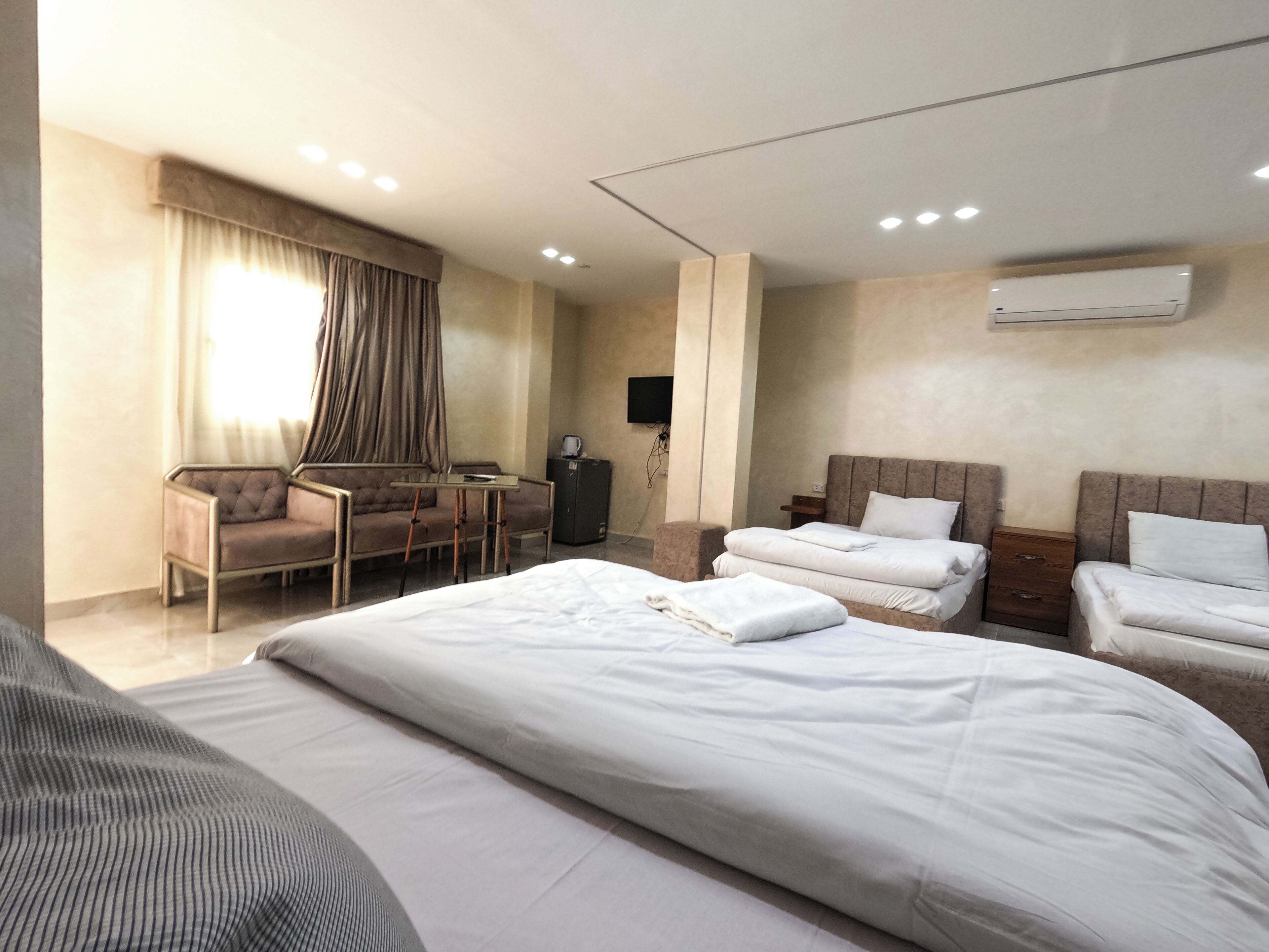 Une chambre d’hôtel avec un grand lit, deux petits lits, un bureau et une chaise.