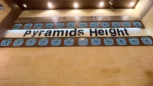 Een bord met de tekst 'Pyramids Height' op een muur met een patroon van tegels.