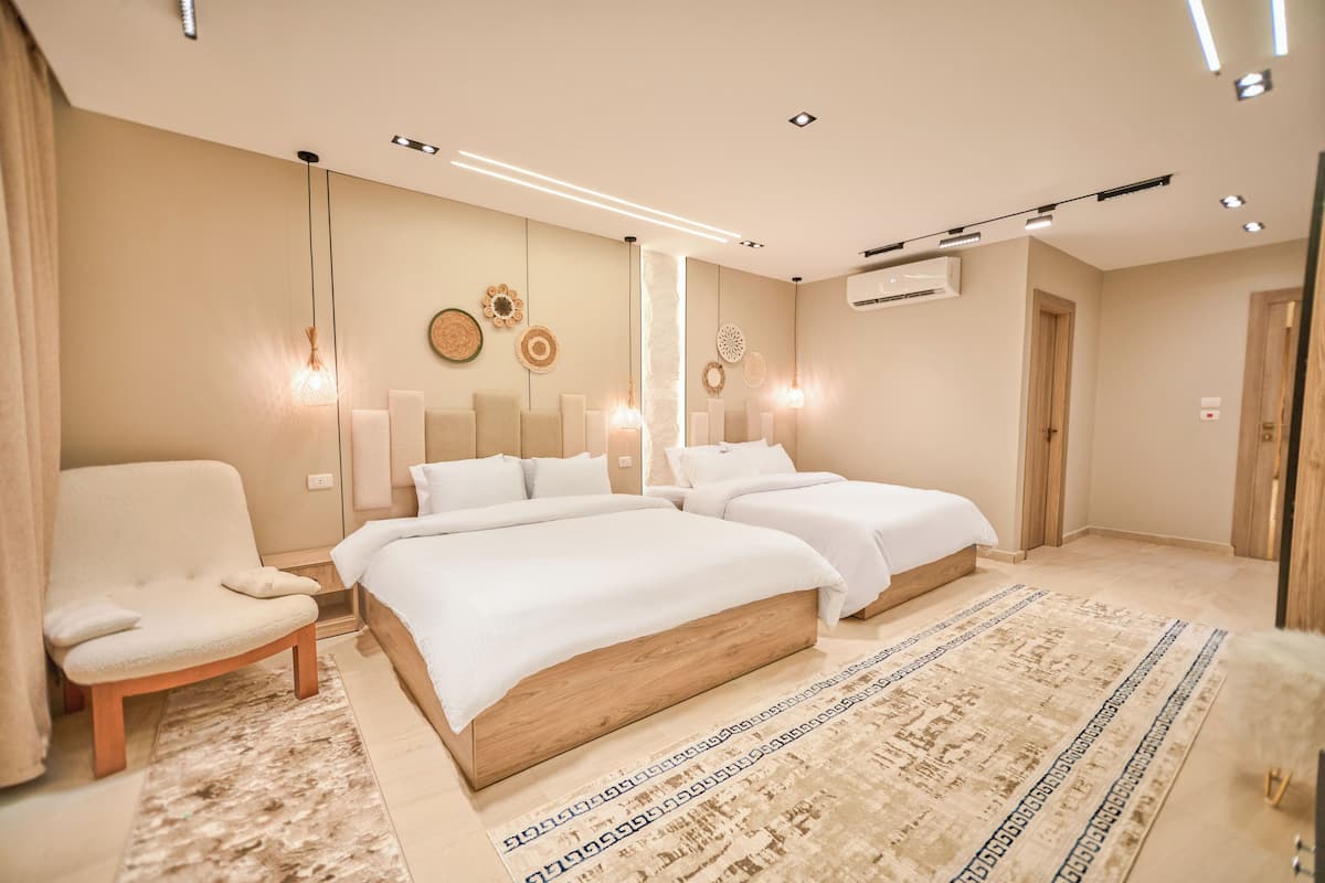 A modern bedroom with two beds, a chair, and decorative wall art.