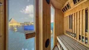 Un interior de madera con un ventanal grande que da a una piscina y una estructura piramidal.