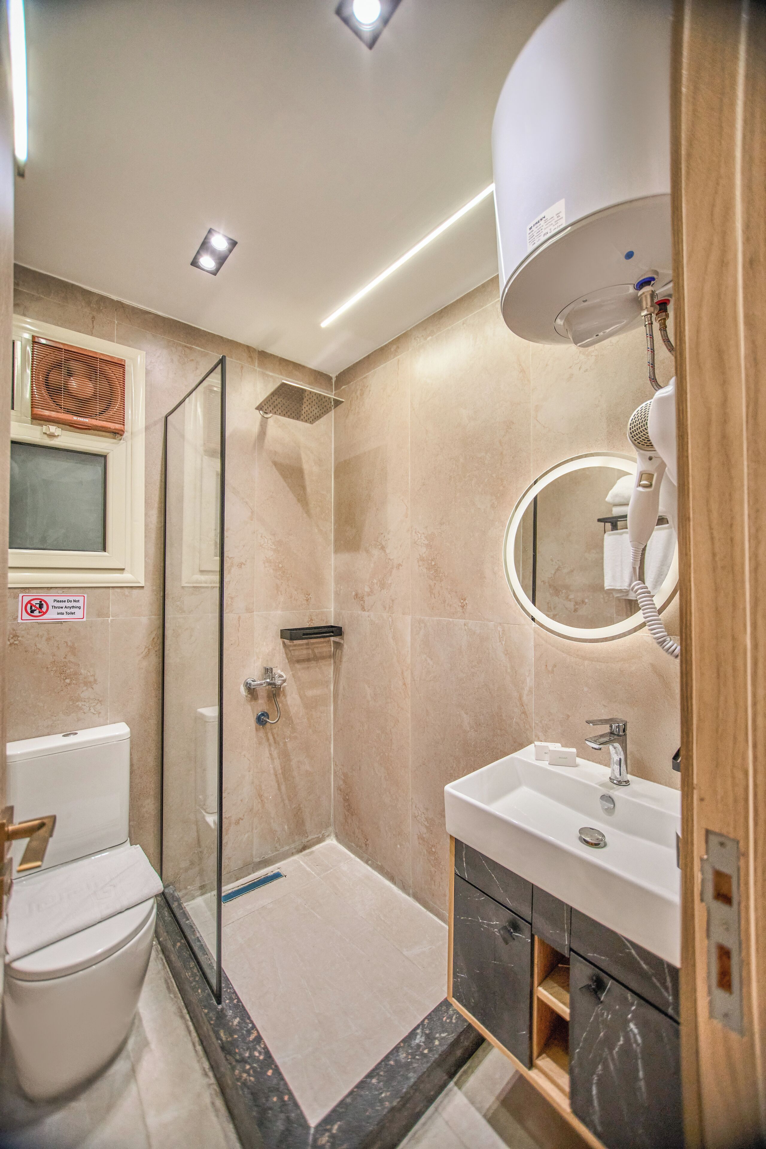 Ein modernes Badezimmer mit Duschkabine aus Glas, Toilette, Waschbecken mit Spiegel und Wandhaartrockner.