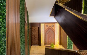 A modern interior with a wooden staircase, a reception desk, and decorative panels. - Pyramids Height Hotel & Pyramids Master Scene Rooftop (Giza)