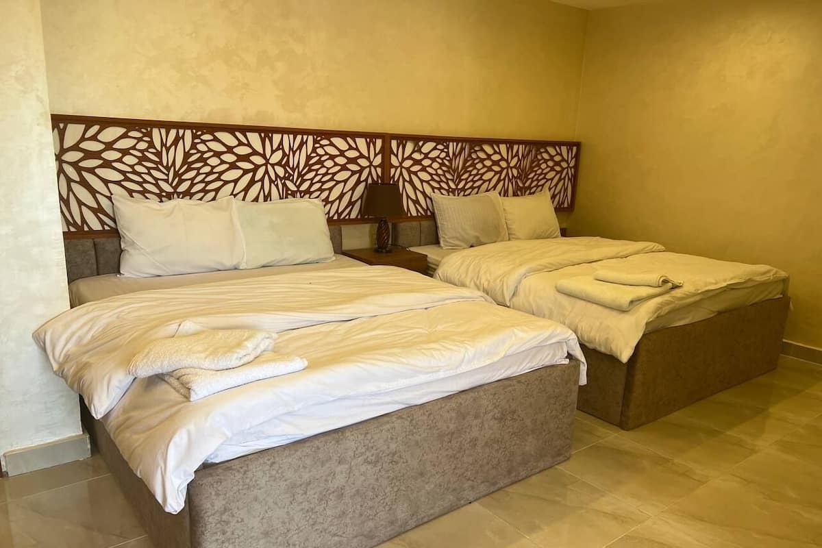 A hotel room with two beds, a decorative headboard, and a tiled floor.