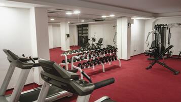 Een fitnessruimte met loopbanden, gewichten en krachtapparaten.