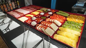 Un bufé con diversas opciones de comida, incluyendo carnes, quesos, frutas y verduras.