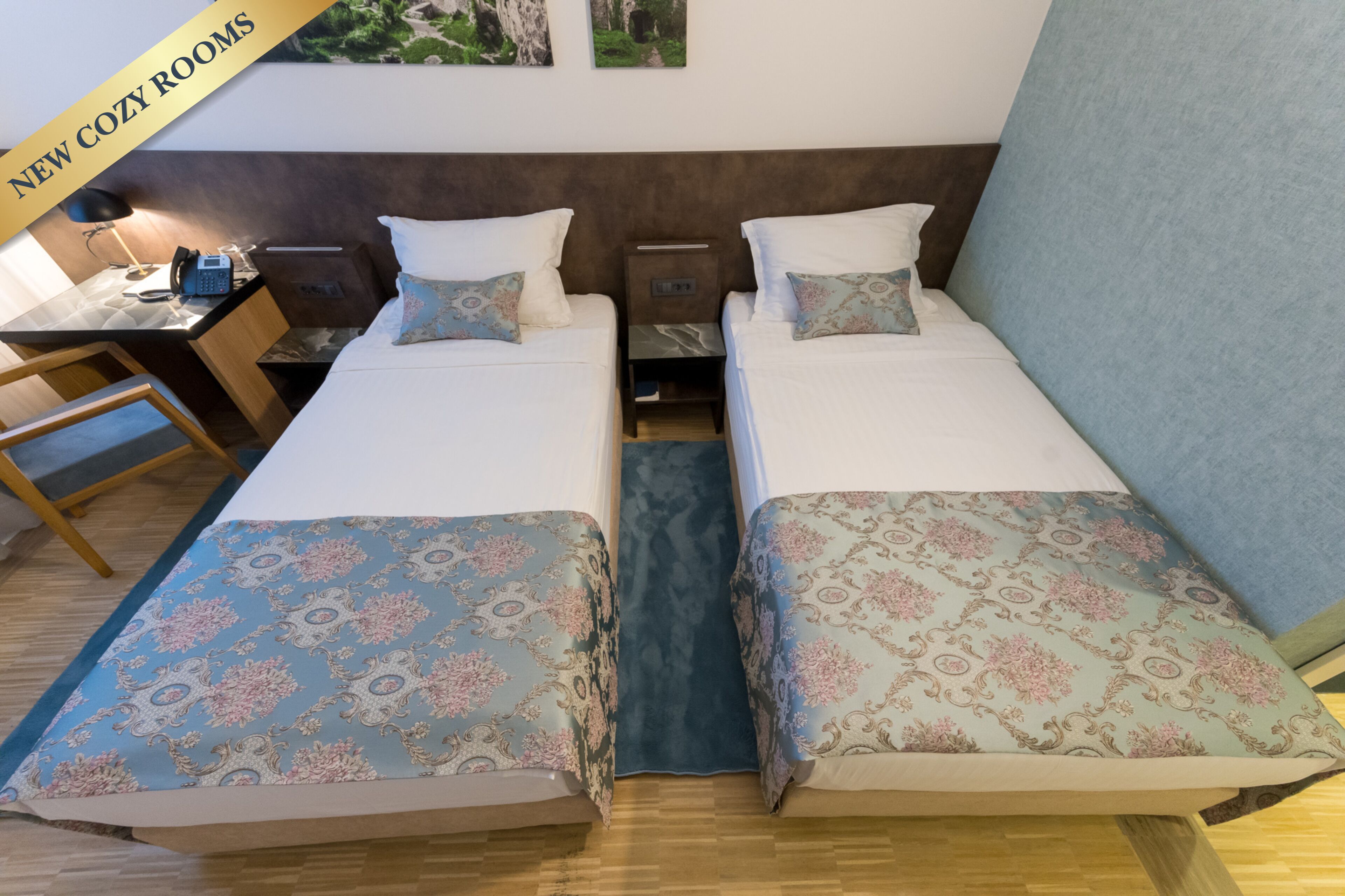 A hotel room with two beds, a desk, and a chair.