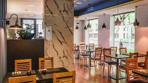 A restaurant with wooden chairs and tables, a marble pillar, and pendant lighting. - Hotel Jarun (Zagreb)