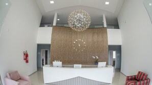 A modern reception area with a central desk, a decorative spherical light fixture, and two patterned chairs. - Hotel HPR Executive (Vitorino)