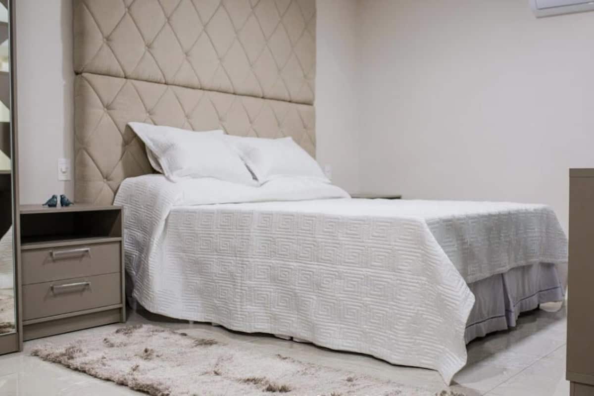 Un dormitorio con cama, mesita de noche, cómoda y espejo.