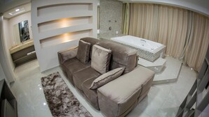 A modern living room with a beige sofa, a large window, and a white bathtub. - Hotel HPR Executive (Vitorino)